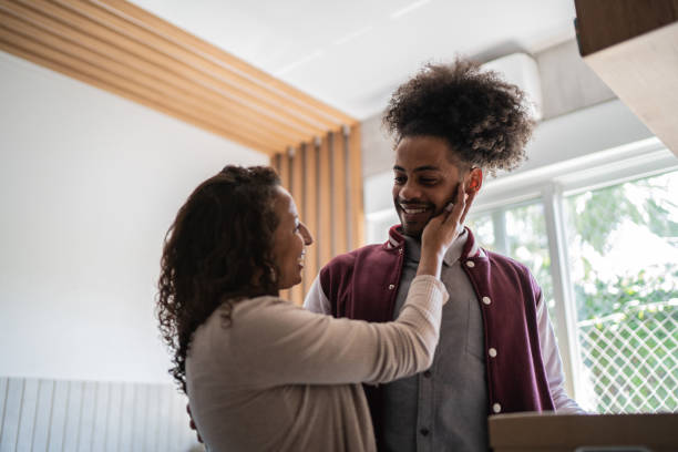 Mother and son embracing at home (he's leaving home) Mother and son embracing at home college student and parent stock pictures, royalty-free photos & images