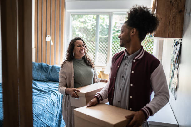 Mother helping son carrying moving boxes to move out from parent's home Mother helping son carrying moving boxes to move out from parent's home college student and parent stock pictures, royalty-free photos & images