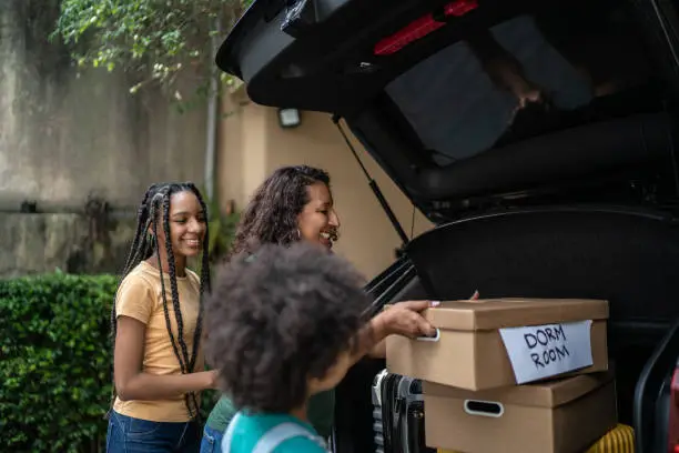 Photo of Mother and daughter putting moving boxes into car trunk