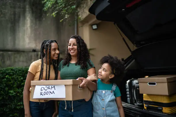 Photo of Mother and daughter putting moving boxes into car trunk