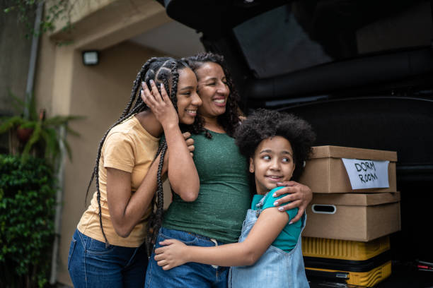 Mother and daughter putting moving boxes into car trunk