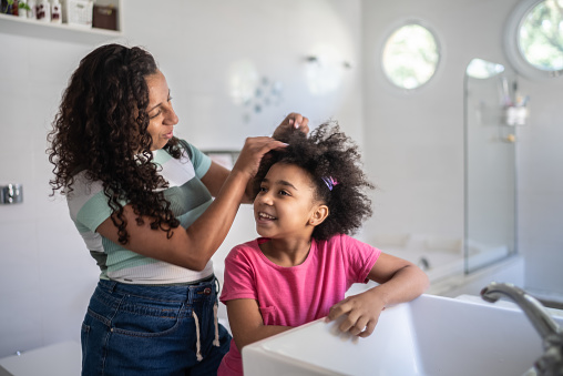 Mother combing daughter's hair at home