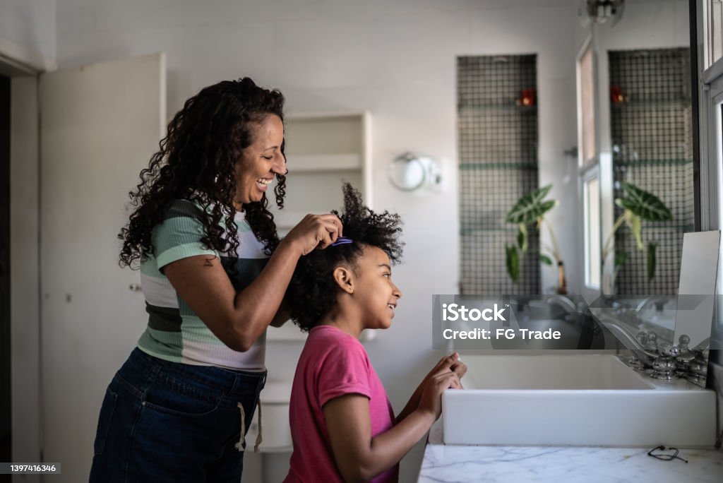 Mother combing daughter's hair at home Mother Stock Photo
