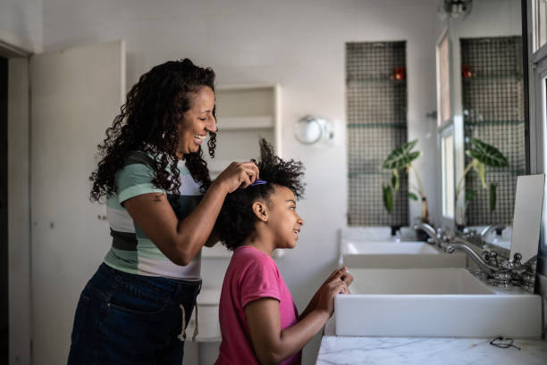 мама расчесывает волосы дочери дома - черный волос стоковые фото и изображения