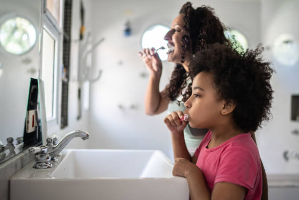 istock Mother and daughter brushing teeth together at home 1397416375