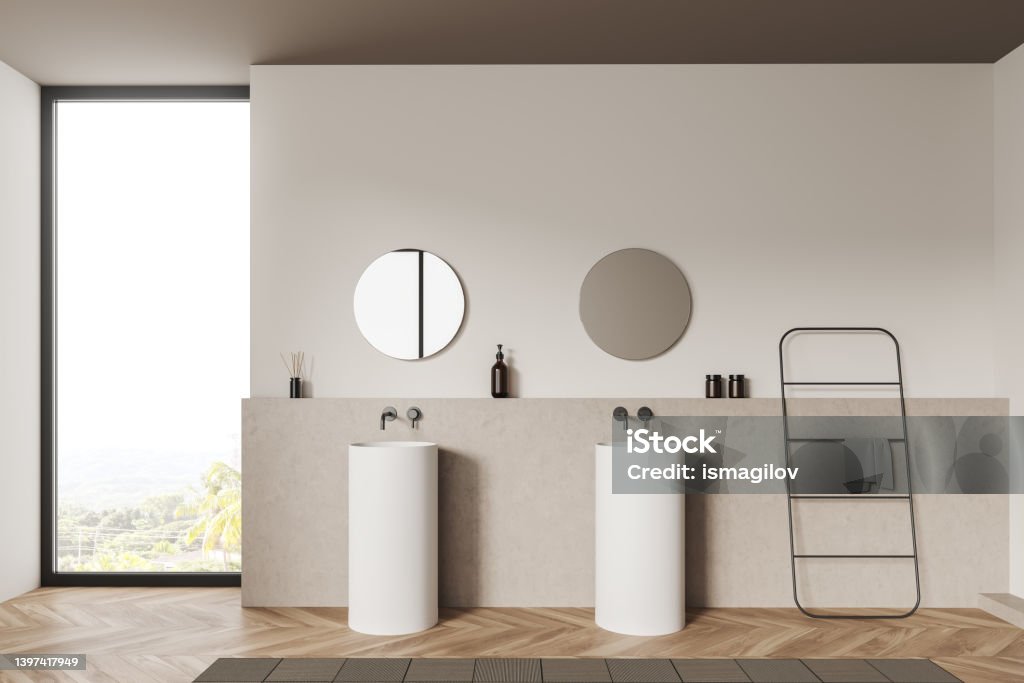 Light bathroom interior with sink and panoramic window, deck and rail ladder Beige bathroom interior with double sink and panoramic window on countryside, towel rail ladder on hardwood floor, bathing accessories. 3D rendering Architecture Stock Photo