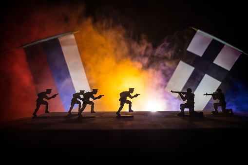 Flags of Finland and Russia on dark background. Conceptual image of war between Russia and Finland using toy soldiers and national flags . Selective focus