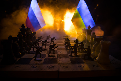 War between Russia and Ukraine, conceptual image of war using chess board, soldiers and national flags on the background of explosion. Ukrainian and Russian crisis. Selective focus