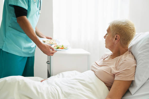 istock Medical worker bringing meal to aging patient 1397422785
