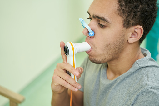 Male putting spirometer tube into mouth and breathing air inside it