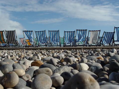 Photograph of empty deck chairs on a stoney beach in Devon