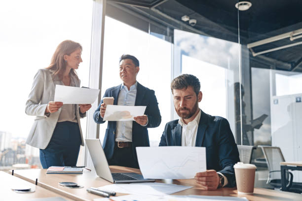 istock Smiling businessmen discussing documents with graphs and charts in a modern office during meeting 1397429950
