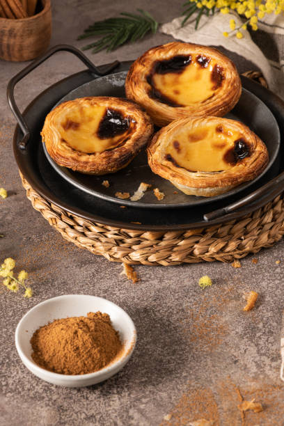 traditional portuguese pastry pastel de nata or pastel de belém served with cinnamon powder in a traditional tray on a rustic board. egg tart - tart dessert tray bakery imagens e fotografias de stock
