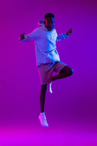 istock Full body portrait of ecstatic African man jumping in modern neon light studio background 1397444554