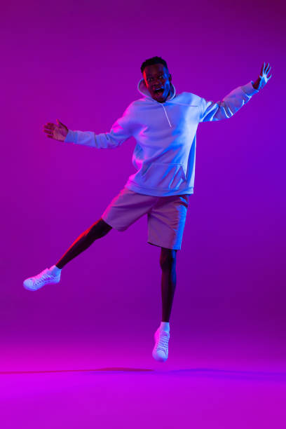 istock Full body portrait of ecstatic African man jumping in modern neon light studio background 1397444561