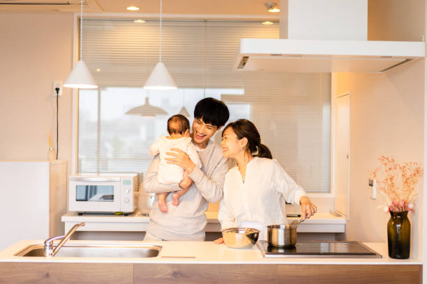 mama kocht in der küche mit papa und baby - two parent family indoors home interior domestic kitchen stock-fotos und bilder