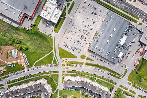 aerial top view of a large number of cars standing on parking lot near shopping center