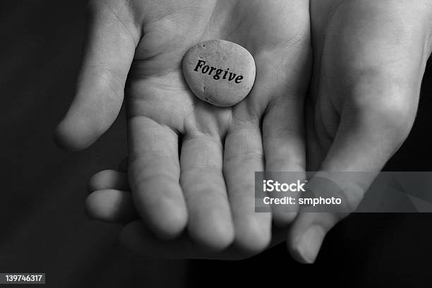 Two Cupped Hands Holding A Stone With Forgive Written On It Stock Photo - Download Image Now