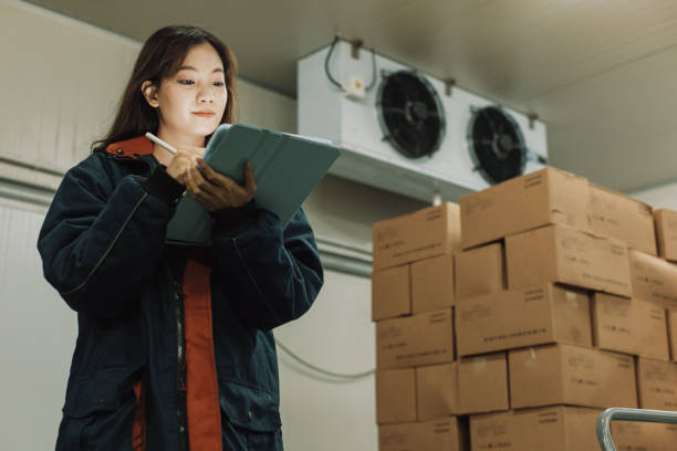 mujer trabajadora de almacenamiento en frío que usa tableta digital para verificar el stock. - distribución de productos alimentarios fotografías e imágenes de stock