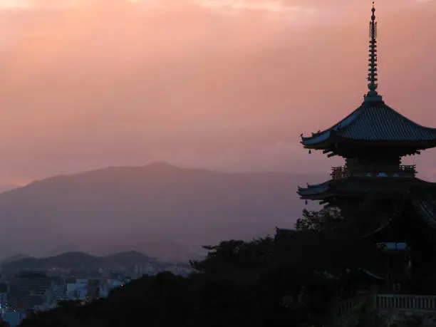 This is a beautiful palace in Kyoto, Japan at sunset with the mountains and city in the background.