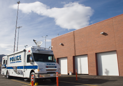 A police communication/command post heavy duty van with antennas extended next to the substation garage.