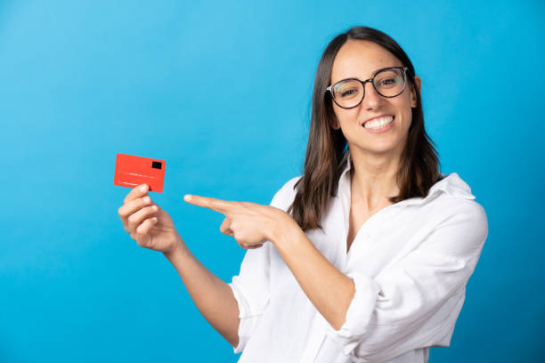 cheerful hispanic woman pointing at credit card - gesturing business looking at camera caucasian imagens e fotografias de stock