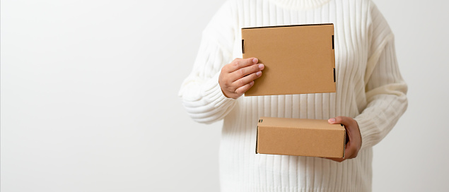 Woman hands holding present box with a ribbon bow. Concept of gift  box minimalist style. Showing brown cardboard boxes delivery someone in special occasions or parcel deliver service.