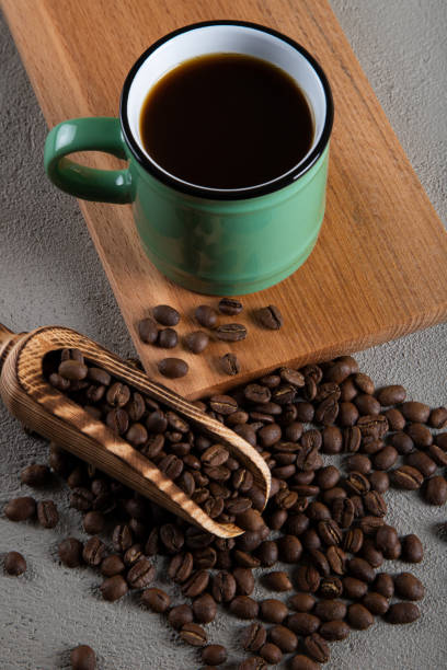 istock Green cup of coffee with coffee beans on concrete background 1397474031