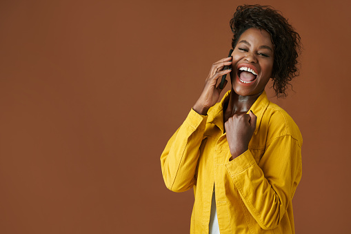 Portrait of excited young Black woman making fist pump gesture when receviving good news on smartphone