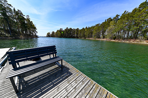 Bench on wooden jetty near green water in Sweden may 9 2022