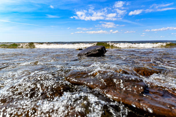 low perspective of wave over stone on beach Sweden may 9 2022