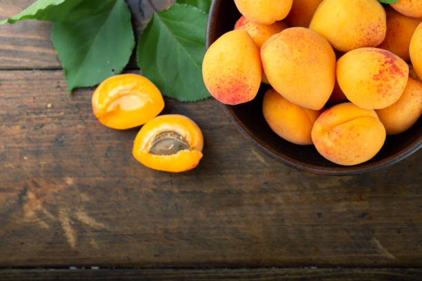 熟したアプリコットとアプリコットは、木製のテーブルの上のボウルに残ります。家庭菜園の新鮮なフルーツ。 - fruit vegetable fruit bowl peaches ストックフォトと画像