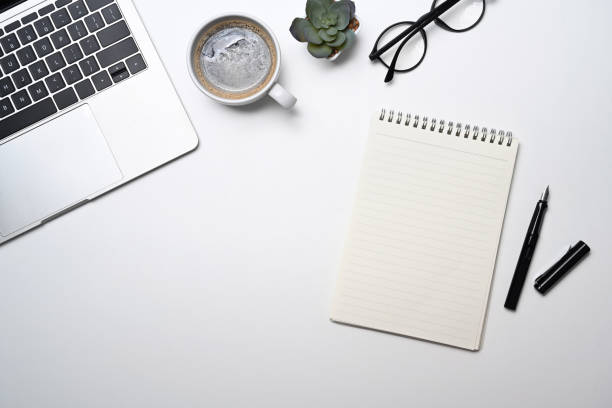 istock Blank notepad, glasses, coffee cup and laptop computer on white background. Top view. 1397481024