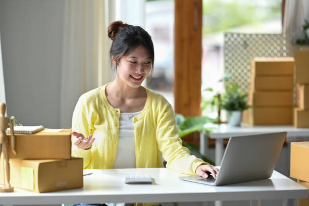 istock Smiling young female entrepreneur checking online order on digital tablet and preparing parcel boxes for delivery to customers. 1397481167