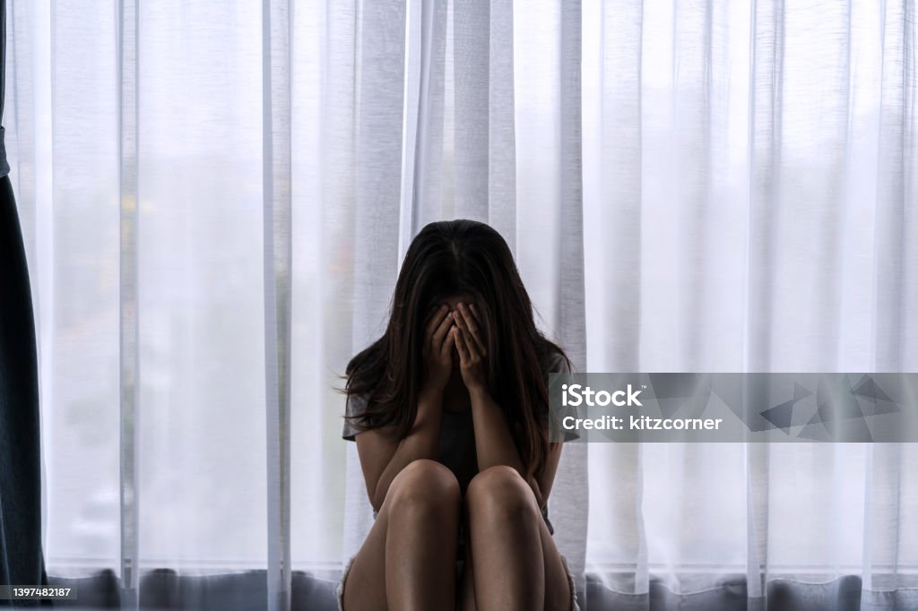 Lonely young woman feeling depressed and stressed sitting in the dark bedroom, Negative emotion and mental health concept Depression - Sadness Stock Photo