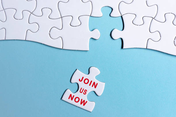 istock White jigsaw puzzle with word join us now over blue background. 1397483753