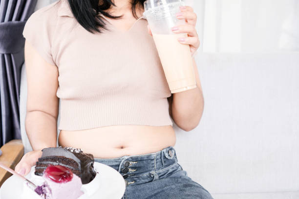 과자를 먹고 마시는 뚱뚱한 여자는 디저트와 우유 커피를 들고 손을 잡는다. - too big cup drink tea 뉴스 사진 이미지