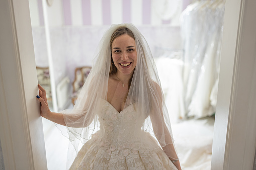 Caucasian female customer, a future bride, at the bridal shop trying on wedding dress