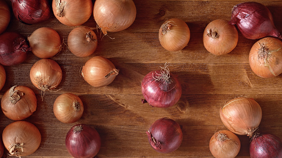 Close-up of red and sweet onions on wooden table.