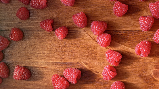 Close-up of raspberry fruits on wooden table.