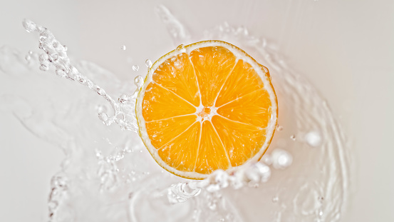 A drop falls from a pipette onto an orange slice, close-up. Vitamin C, skin care