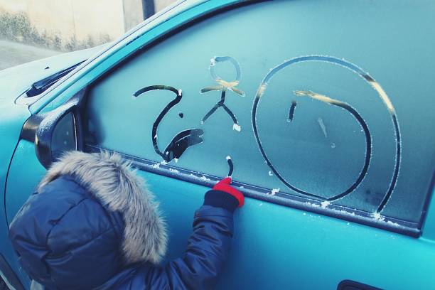 ein junge, der mit seinem finger bilder auf ein autofenster zeichnet. - window frozen car cold stock-fotos und bilder