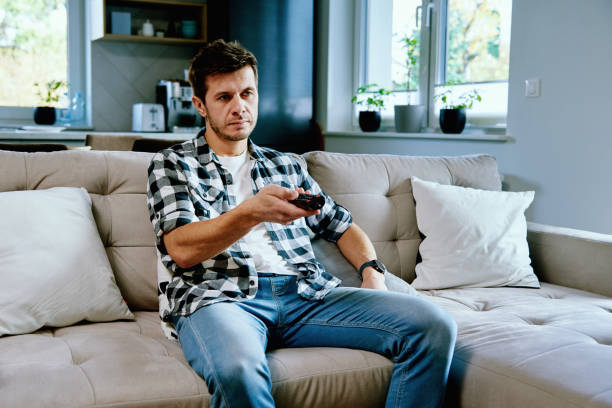 istock Man Sitting On Sofa And Watching Tv, Switch Channels Using Remote Control. Resting At Home 1397490616