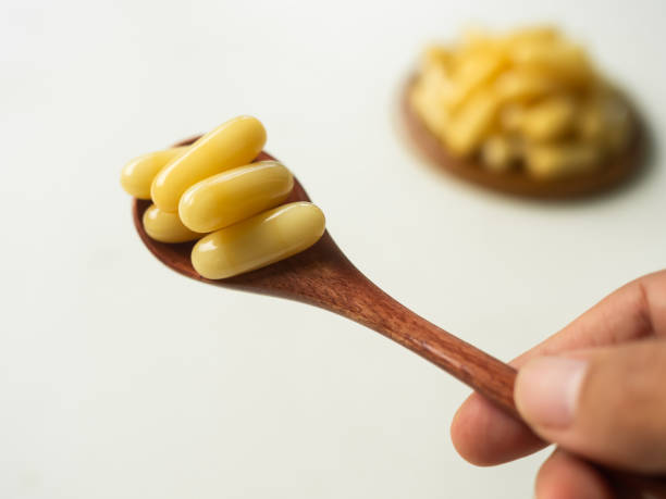 Royal jelly capsules on wooden spoon. stock photo