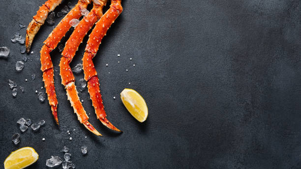 Crab legs top view on dark background. Delicatessen crab seafood on black slate table. Crustacean seafood aesthetics. Luxury crab meat food flat lay. Seafood menu background with alaskan crab legs vista superior de patas de cangrejo sobre fondo oscuro. delicatessen cangrejo marisco sobre mesa de pizarra negra. estética de los crustáceos marinos. comida de carne de cangrejo de lujo plana puesta. fondo del menú de mariscos con patas de cangrejo de
