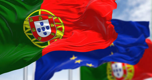 détail du drapeau national du portugal agitant dans le vent avec le drapeau flou de l’union européenne en arrière-plan - portuguese culture portugal flag coat of arms photos et images de collection