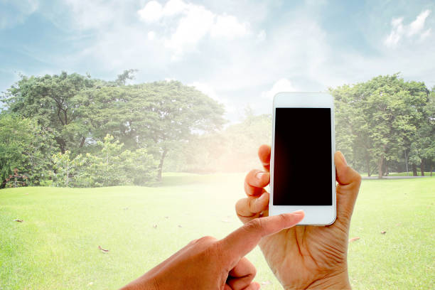 istock hand hold and touch screen smart phone on big trees in the garden with burst light 1397497747