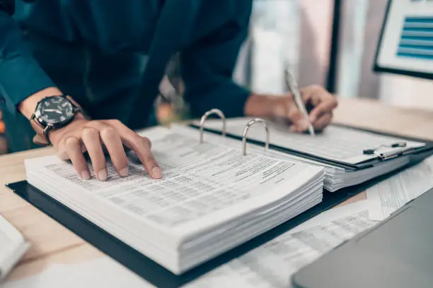 Photo of Investors working on desk office and finger  pointing to check tracking cost, balance, profit and  currency. Accounting and  Financial concept.