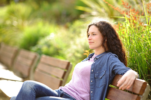 Relaxed woman contemplating from bench in a park