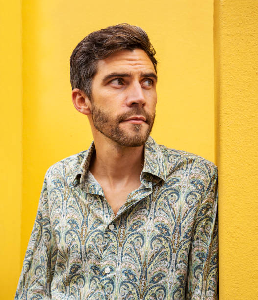 istock Stylish young man leaning against a yellow wall outside 1397506626